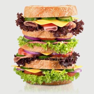 this sandwich is piled high with fresh lettuce, deli meat and cheese.