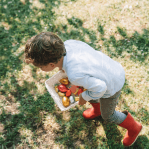 Child enjoying a spring Easter egg hunt outdoors, collecting colorful eggs in a basket North of Boston