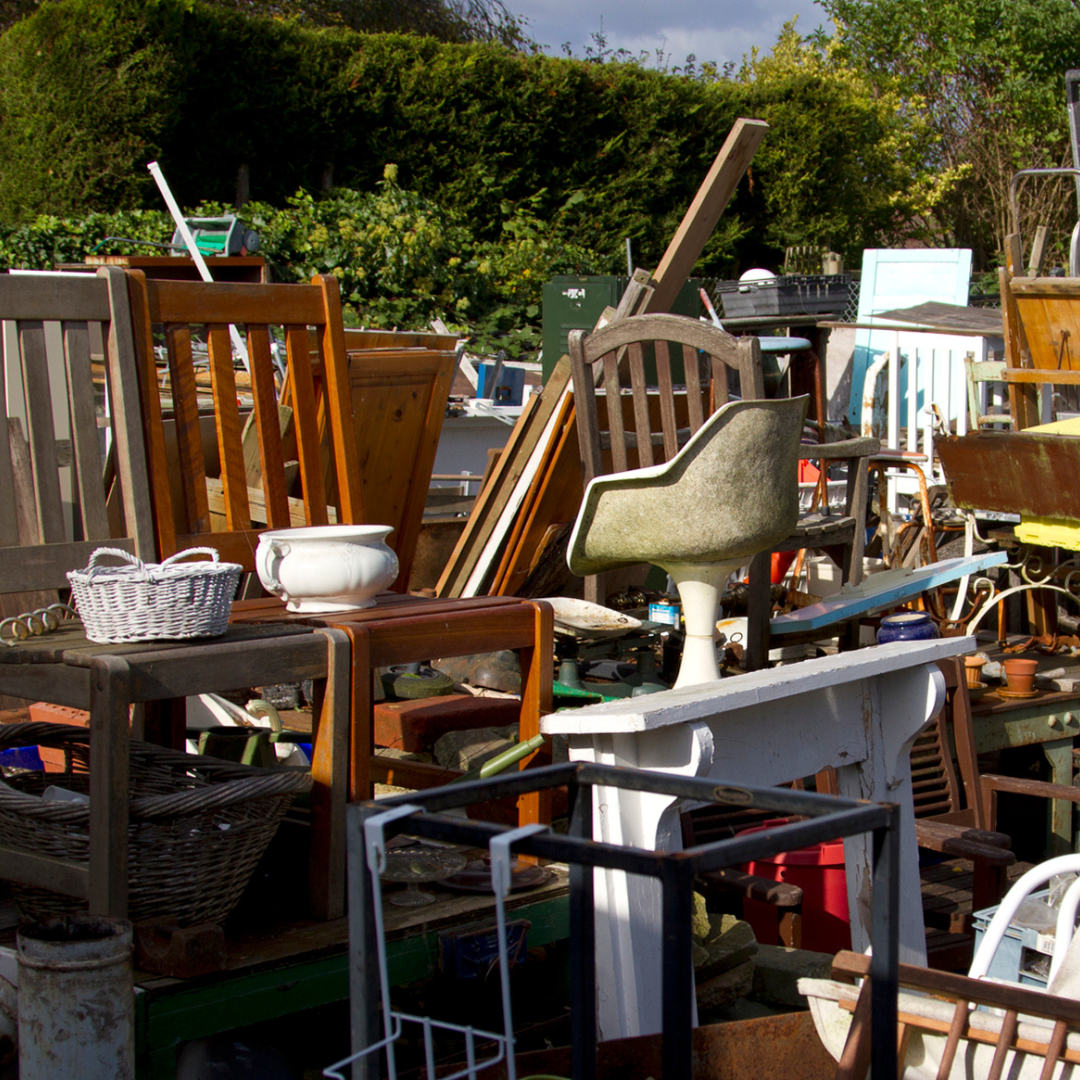 Pile of unwanted furniture and household items including chairs, tables, and miscellaneous clutter ready for junk removal in a residential yard