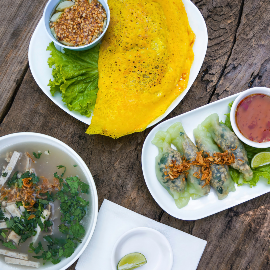 Assorted Thai dishes including crispy crepe, dumplings, and herb soup on a wooden table representing Thai cuisine popular at restaurants North of Boston