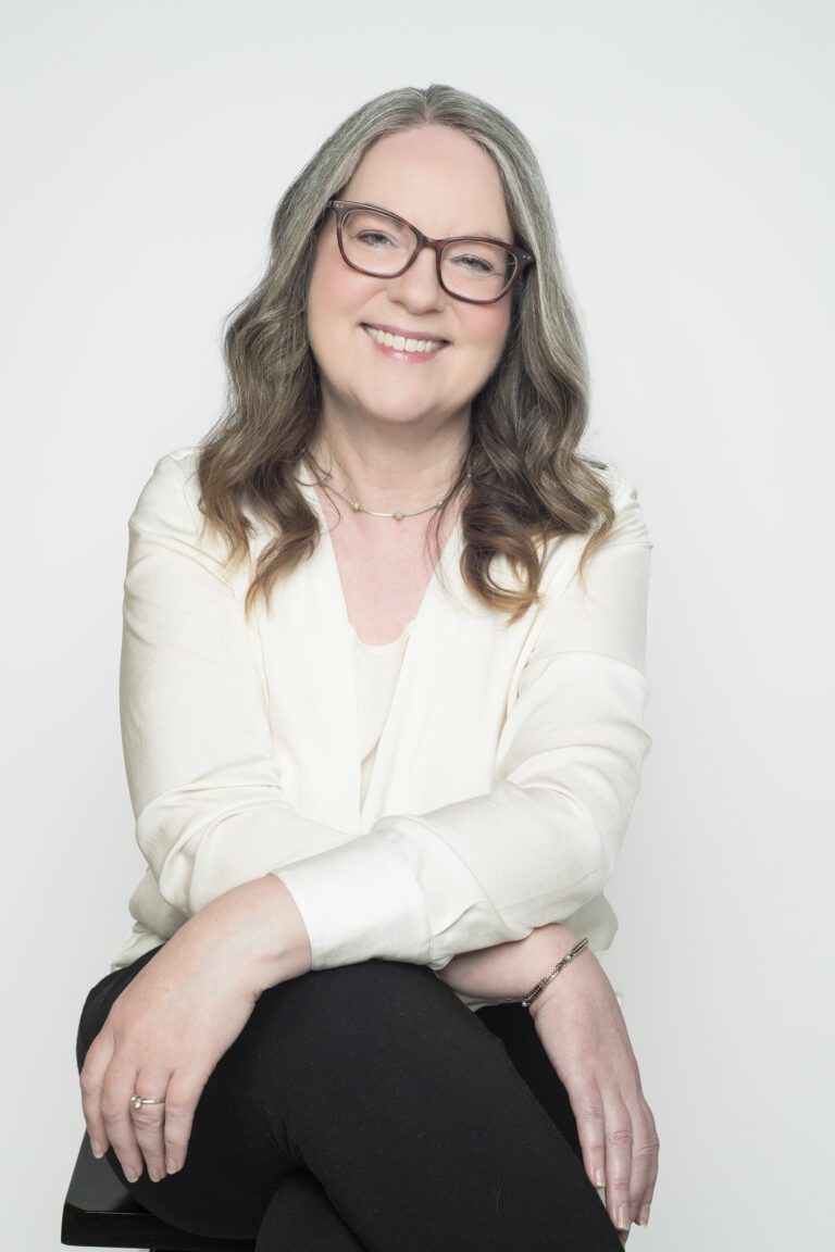 Jodi Crowley, Realtor® with North of Boston Lifestyle, smiling in a professional portrait wearing a cream blouse and glasses