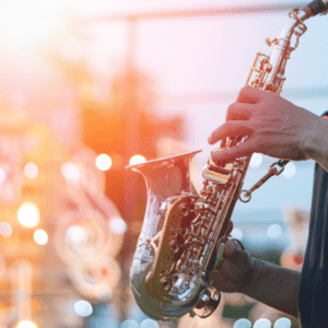 A musician plays a gleaming saxophone under warm stage lights with bokeh in the background — capturing the spirit of the 15th Annual Arlington Jazz Festival, April 8–12, 2026.